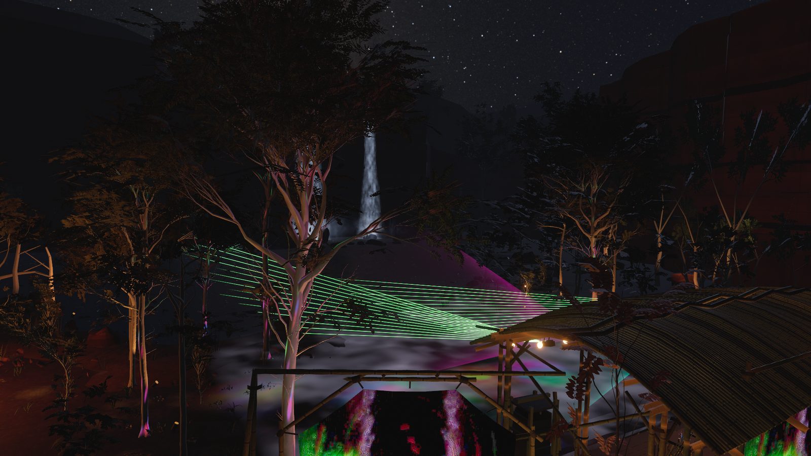 Looking down over the clearing at night: the stage roof, lasers through the trees, the waterfall lit on the escarpment behind